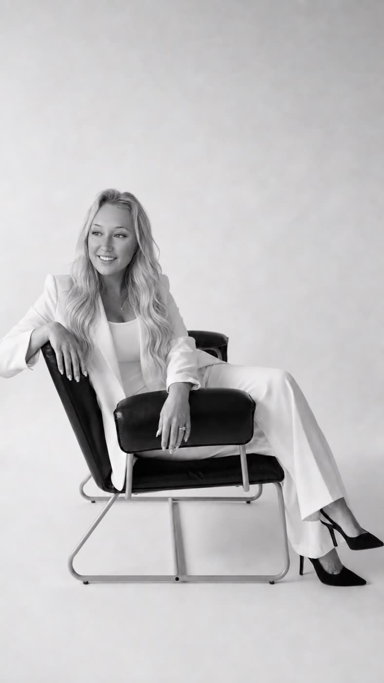 Black and white portrait of Hannah Lee seated in a white suit, smiling