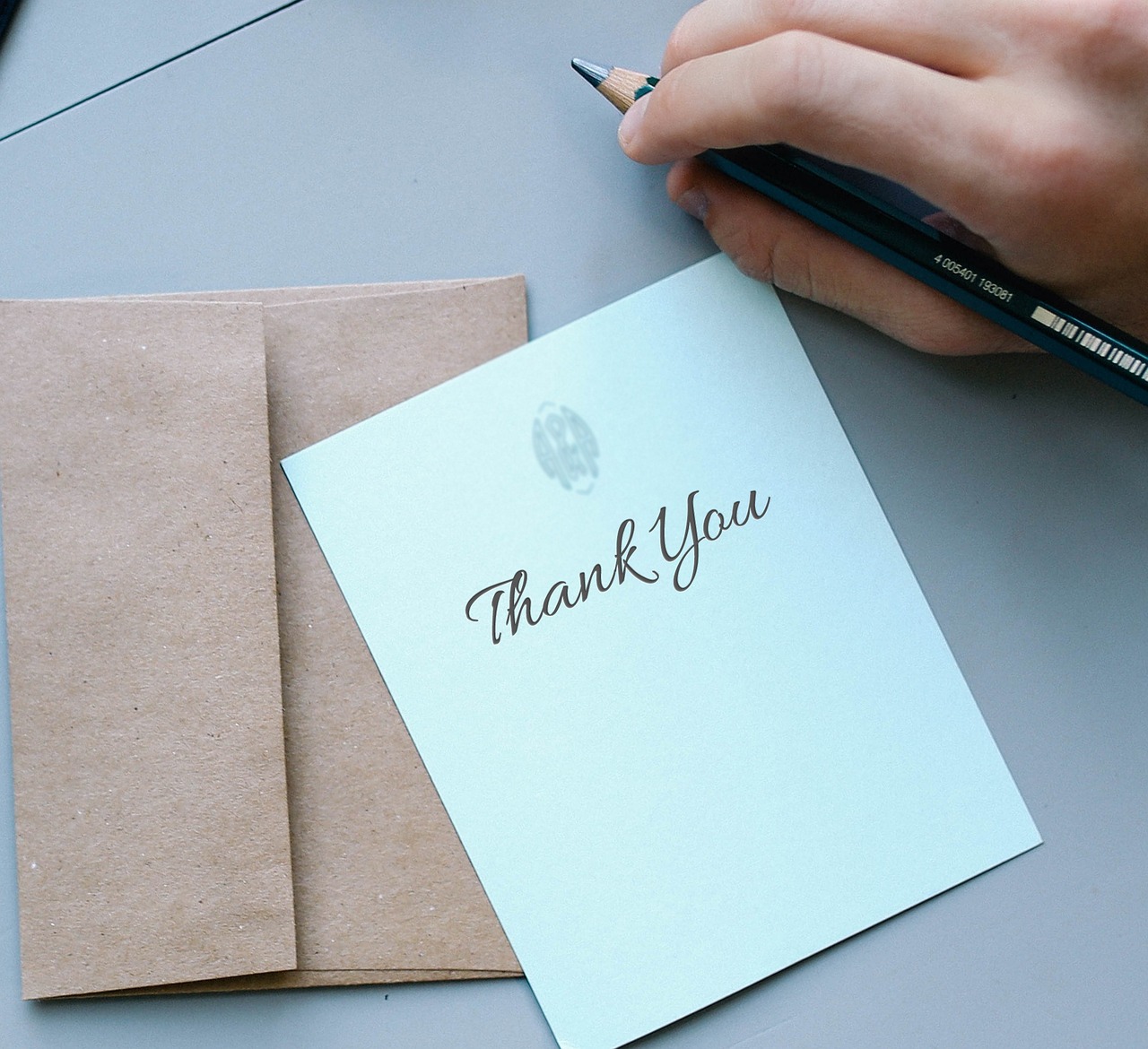 A handwritten thank you card resting on a kraft paper envelope