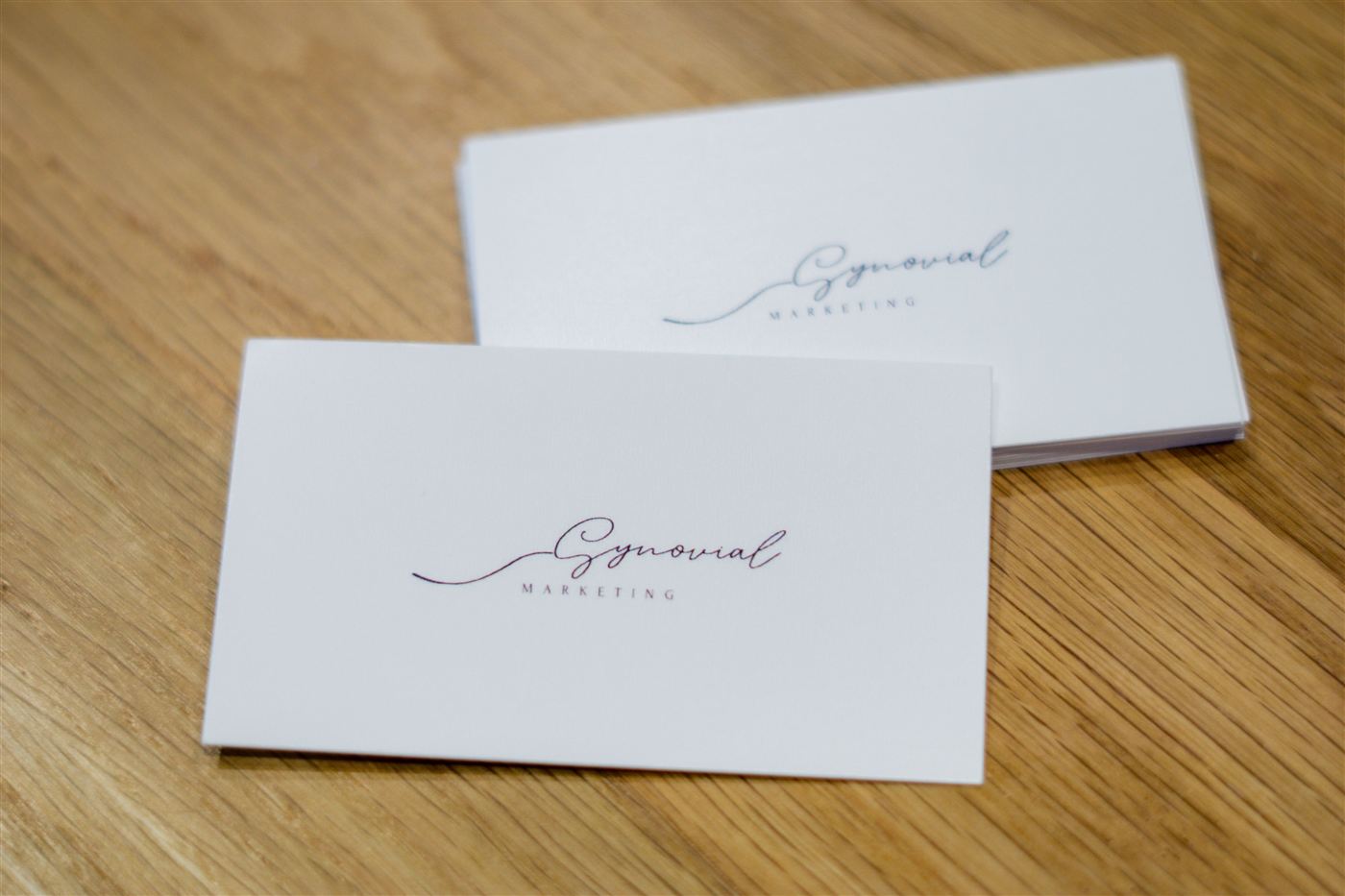 The first Synovial Marketing business cards laid out on a wood table